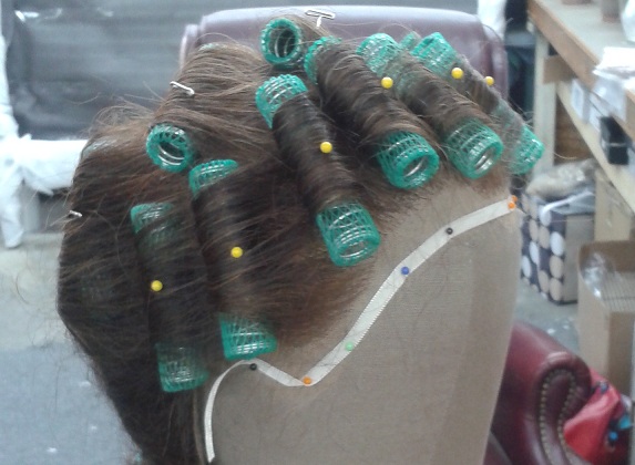 A lace front wig blocked on a canvas head and set into rollers