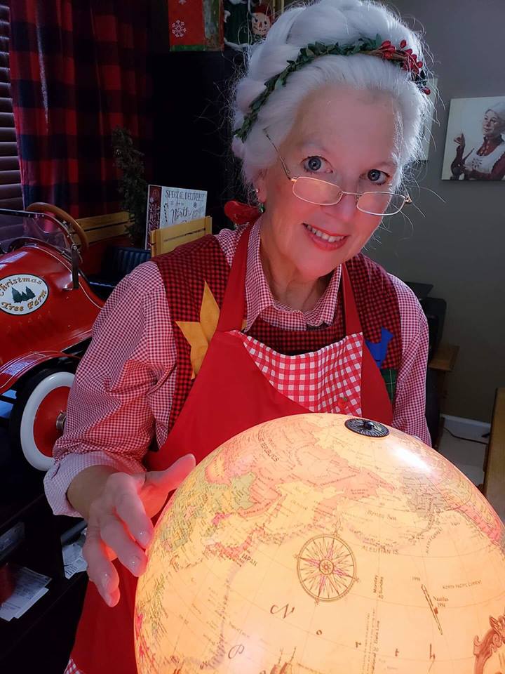 Mrs. Claus looking at the North Pole on a globe