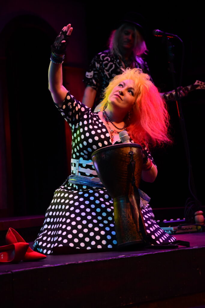 Cyndee Lauper tribute artist Becky from So Unusual, performing onstage in a custom red and yellow wig and black and white polka dot dress