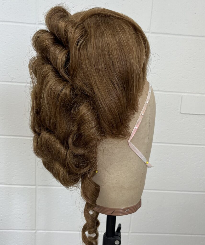 an 18th century styled wig on a brown canvas head against a white background